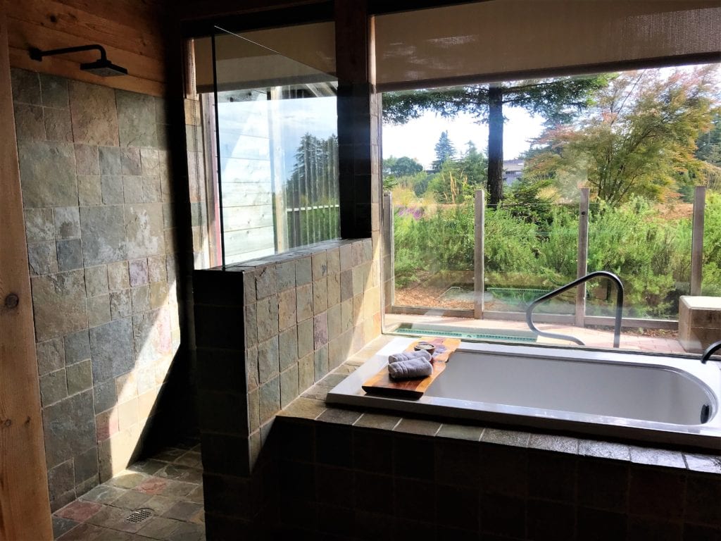 A oversized soaking tub and shower with views of the private patio and hot tub